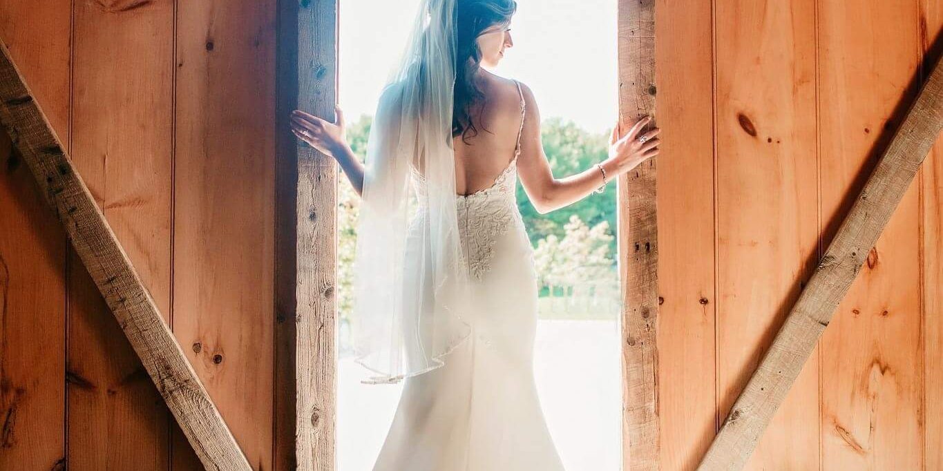 bride opening the barn doors causing her to be backlit by the sunlight