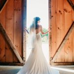 bride opening the barn doors causing her to be backlit by the sunlight