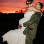 groom carrying the bride at sunset